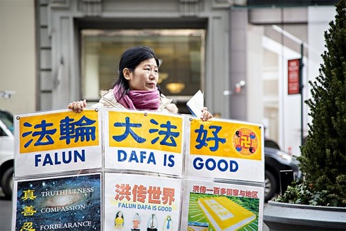 Wang Huijuan, ispred zgrade Empire State Building na Manhattanu u New Yorku, 12. siječnja 2017., drži u rukama plakat kako bi pomogla kineskim turistima da shvate činjenice o progonu Falun Gonga u Kini. (Samira Bouaou / Epoch Times)