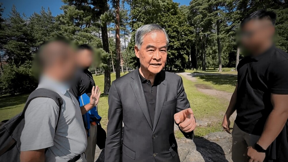 Leung Chun-ying (u sredini) prilazi i verbalno se sukobljava s praktikantom Falun Gonga u javnom parku u Finskoj.